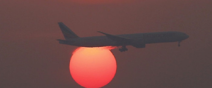 A plane flies over the setting sun in the sky at Beijing International Airport, China, March 2, 2016.  REUTERS/Kim Kyung-Hoon/File Photo